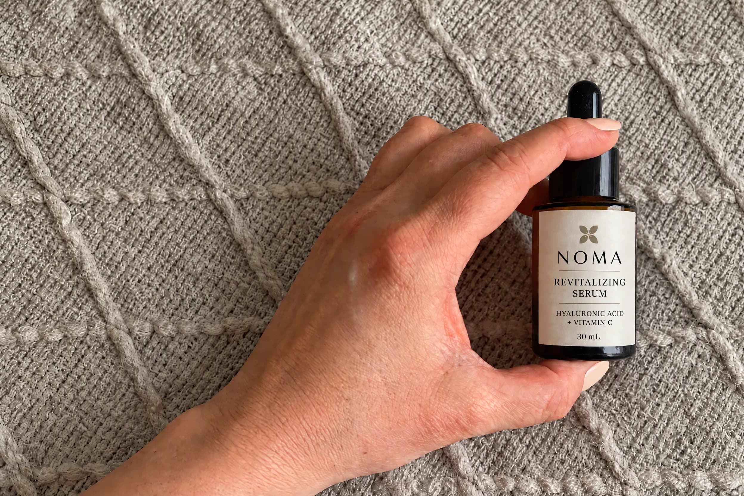 NOMA serum source based on a real phone photo, with the demo label and knit background extension edited using AI